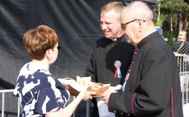 Burmistrz częstuje chlebem księży.